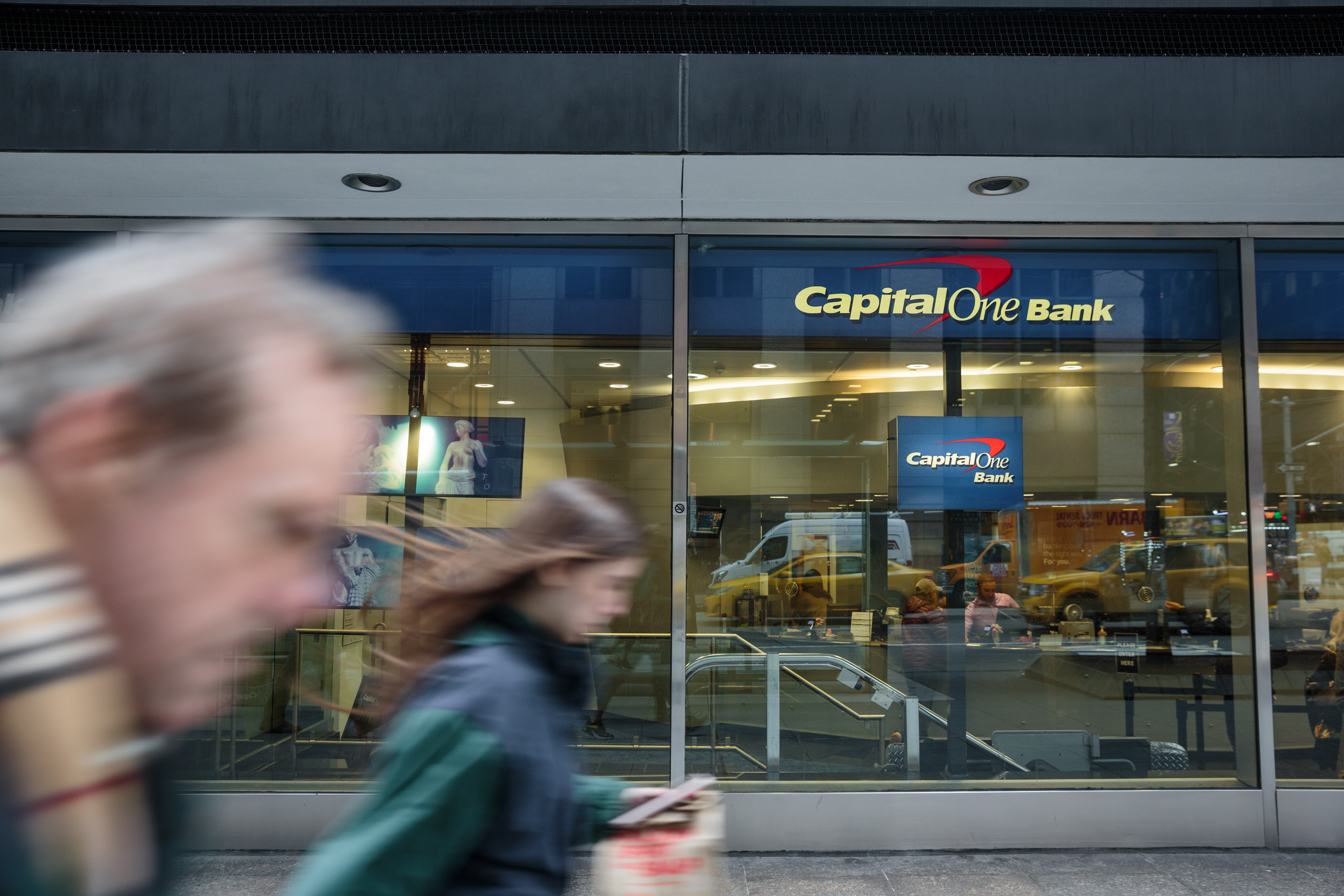 Pedestrians pass in front of a Capital One Financial Corp. bank branch in New York, U.S. Photographer: Sarah Blesener/Bloomberg