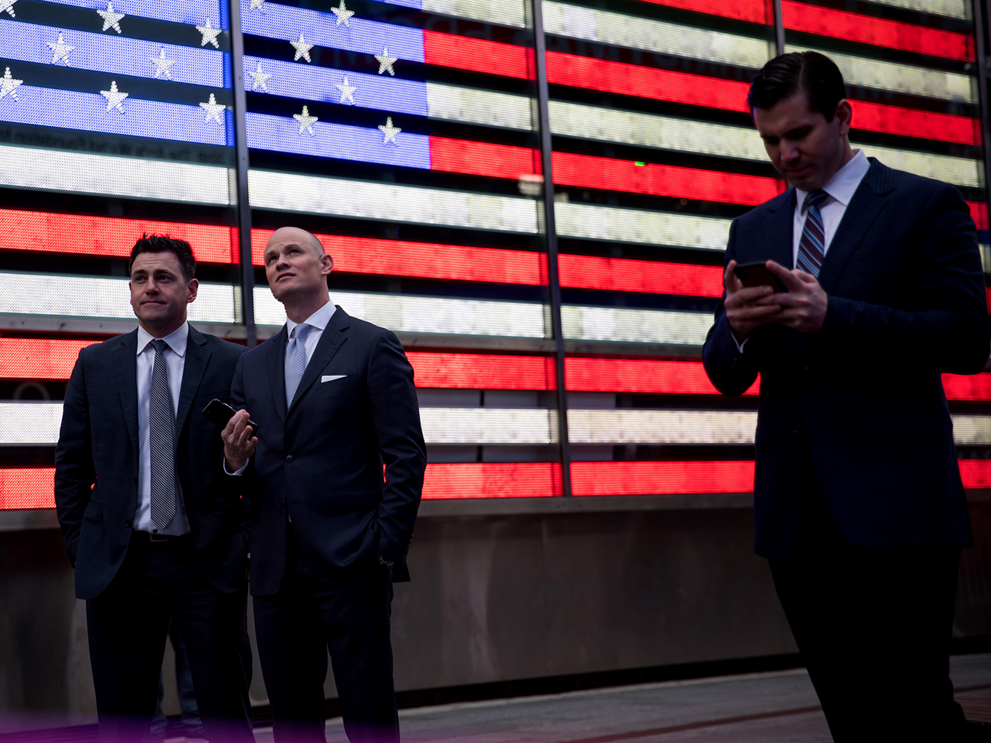 Pedestrians stand in front of an illuminated American flag in the Times Square neighborhood of New York. Photographer: Michael Nagle/Bloomberg