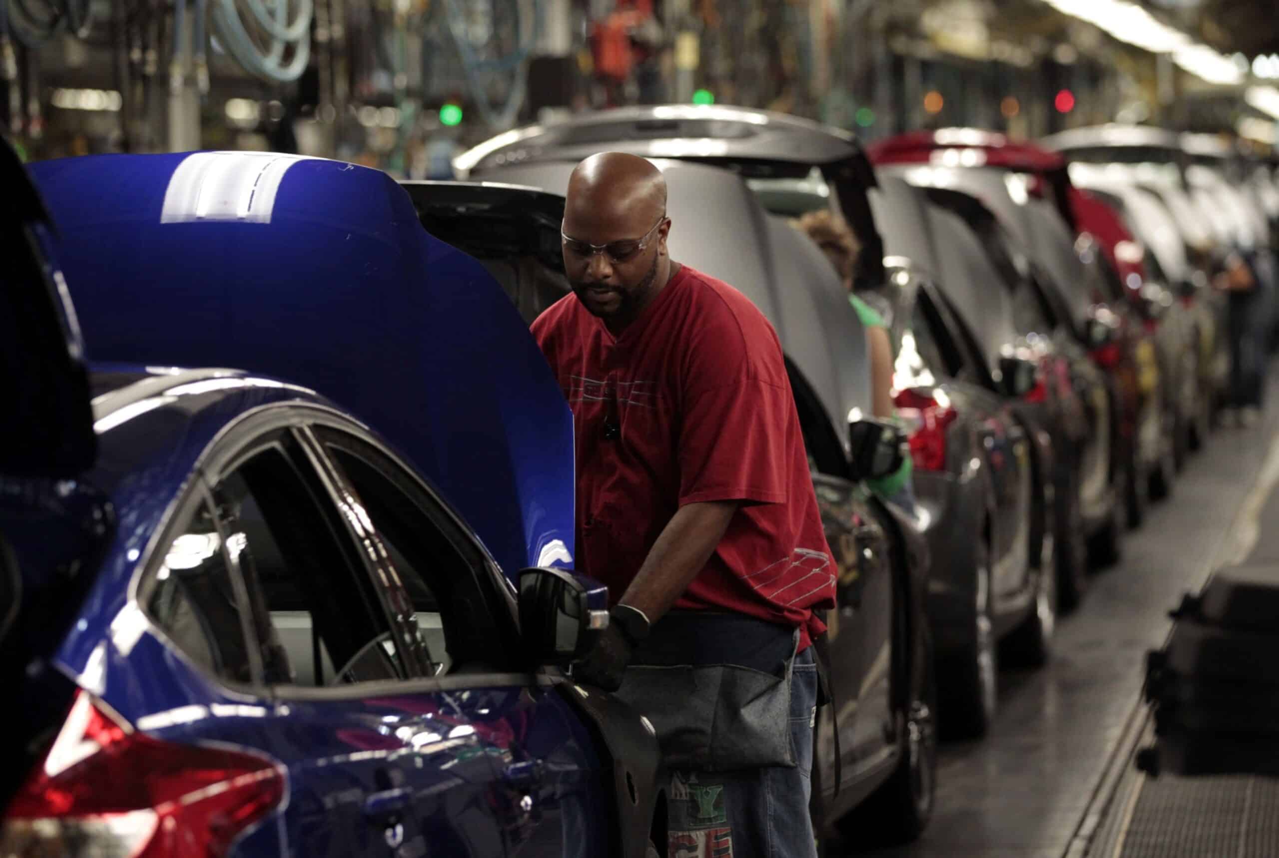 Ford Motor Company line worker Teron Stewart works on a Focus vehicle on the line as they celebrate the 100th Anniversary of the Moving Assembly Line at their Michigan Assembly Plan in Wayne, Michigan, U.S., on Monday, October 7, 2013.  Photographer: Jeff Kowalsky/Bloomberg *** Local Caption ***