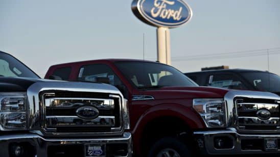 A Ford Motor Co. logo stands behind a row of F-250 pickup trucks at the Rob Baker Ford dealership in Plainfield, Illinois, U.S., on Wednesday, July 23, 2014.