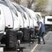 A manager inspects a row of travel trailers at Motor Sportsland RV dealership in Salt Lake City, Utah, U.S., on Monday, April 6, 2020. Amid the coronvirus, government agencies are obtaining RVs to house the homeless and provide housing for medical workers who can not return home in fear of spreading the virus.