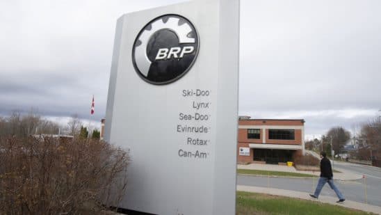 A pedestrian walks past signage for a BRP manufacturing facility in Valcourt, Quebec, Canada, on Wednesday, Oct. 28, 2020. BRP Inc. says production shutdowns depleted its inventory and dragged down revenues in its second quarter, but rising demand buoyed profits as fun-seekers turned to power sports for pandemic recreation, The Toronto Star reported.