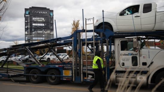 A worker loads up vehicles for inspection before being placed for sale at a Carvana Vending Machine location in Novi, Michigan, U.S., on Wednesday, Nov. 3, 2021. Hertz Global Holdings Inc., fresh off a blockbuster order for 100,000 Teslas, reached an exclusive agreement to supply Uber drivers with electric vehicles and signed up Carvana Co. to dispose of rental cars it no longer wants.