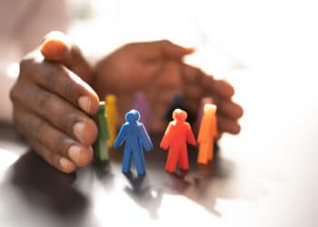Hands wrapped around colored figurines to signify inclusion