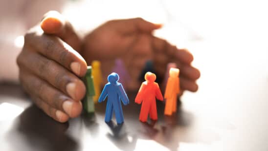 Hands wrapped around colored figurines to signify inclusion