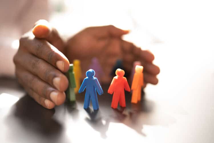 Hands wrapped around colored figurines to signify inclusion