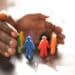 Hands wrapped around colored figurines to signify inclusion