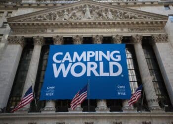 Camping World Holdings Inc. signage is displayed as American Flags fly outside of the New York Stock Exchange (NYSE) during the company's initial public offering (IPO) in New York, U.S., on Friday, Oct. 7, 2016. U.S. stocks fell after jobs data showing steady growth in the labor market likely kept the Federal Reserve on track to tighten monetary policy this year as investors turn to the third-quarter earnings season.