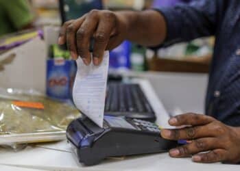 An employee prepares to tear off a receipt from a payment terminal at a supermarket