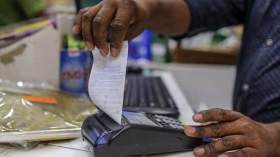 An employee prepares to tear off a receipt from a payment terminal at a supermarket