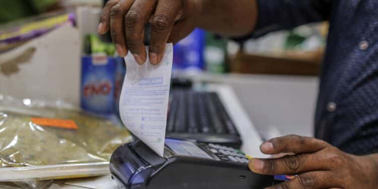 An employee prepares to tear off a receipt from a payment terminal at a supermarket