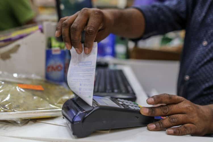 An employee prepares to tear off a receipt from a payment terminal at a supermarket