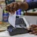 An employee prepares to tear off a receipt from a payment terminal at a supermarket