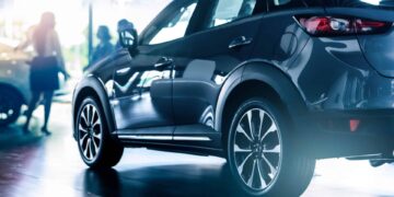 New suv car in modern luxury showroom on blur saleswoman and customer