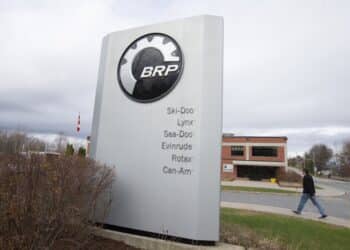 A pedestrian walks past signage for a BRP manufacturing facility in Valcourt, Quebec, Canada, on Wednesday, Oct. 28, 2020. BRP Inc. says production shutdowns depleted its inventory and dragged down revenues in its second quarter, but rising demand buoyed profits as fun-seekers turned to power sports for pandemic recreation, The Toronto Star reported.