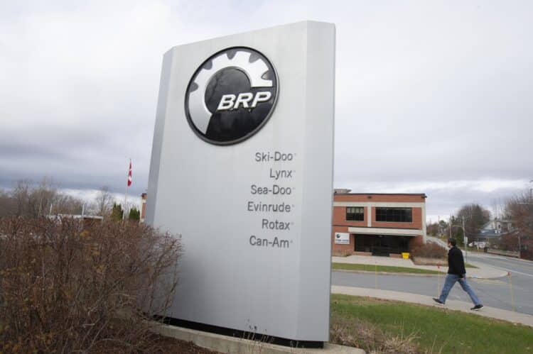 A pedestrian walks past signage for a BRP manufacturing facility in Valcourt, Quebec, Canada, on Wednesday, Oct. 28, 2020. BRP Inc. says production shutdowns depleted its inventory and dragged down revenues in its second quarter, but rising demand buoyed profits as fun-seekers turned to power sports for pandemic recreation, The Toronto Star reported.