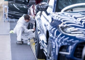 An employee works on a wheel arch of an Aston Martin sport utility vehicle.