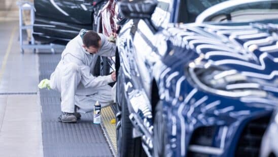 An employee works on a wheel arch of an Aston Martin sport utility vehicle.