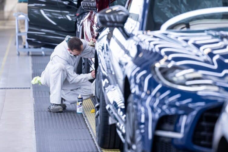 An employee works on a wheel arch of an Aston Martin sport utility vehicle.