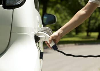 A hand plugs in an EV charger