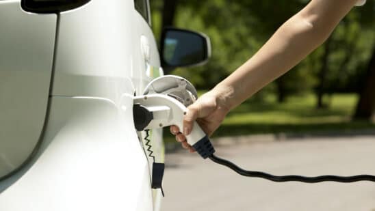 A hand plugs in an EV charger