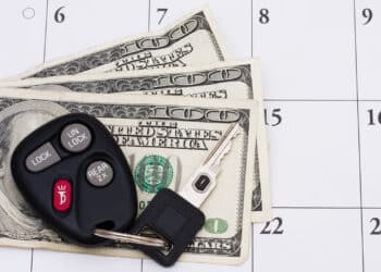 Set of car keys sitting on money on a calendar.