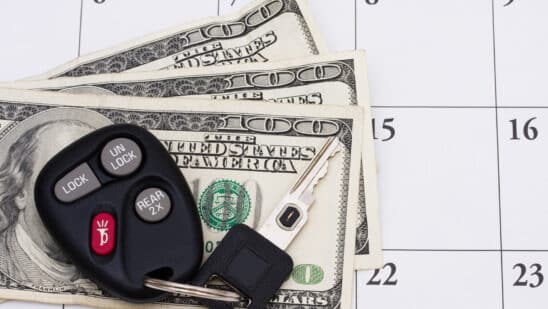 Set of car keys sitting on money on a calendar.