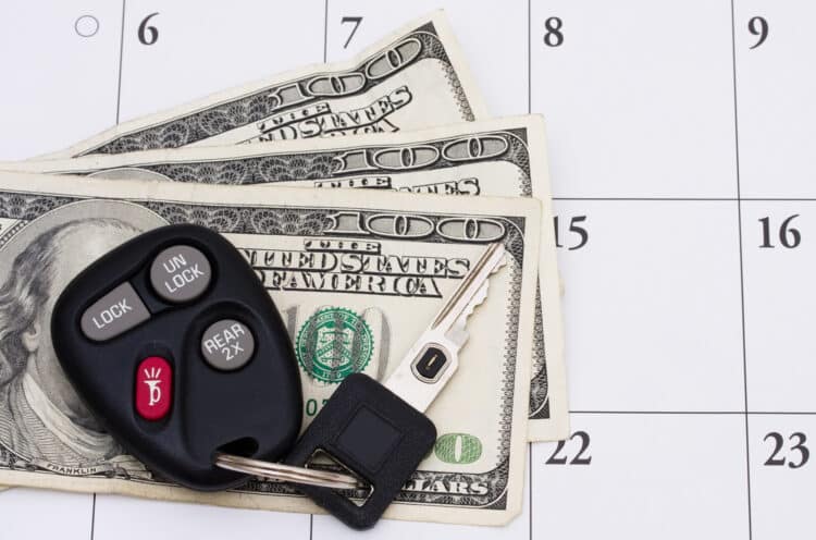 Set of car keys sitting on money on a calendar.