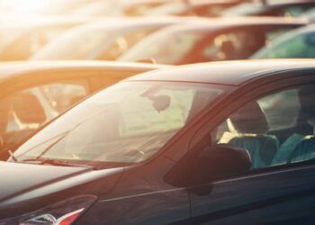 tops of new cars in lot with sunset in background