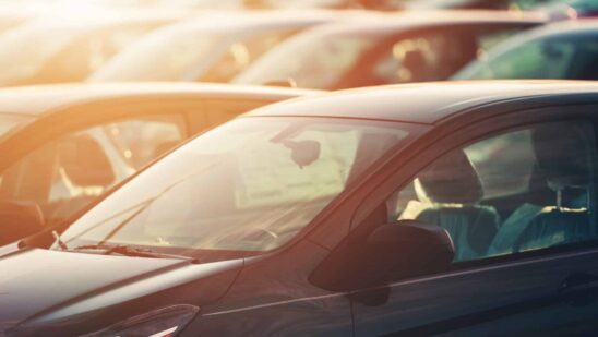 tops of new cars in lot with sunset in background
