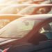 tops of new cars in lot with sunset in background