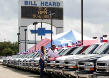 Two people looking at a car in a sales lot in Texas