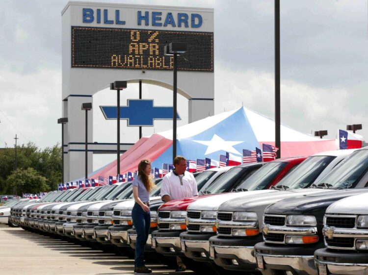 Two people looking at a car in a sales lot in Texas