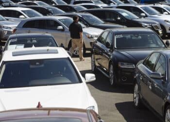 A car dealer walks past cars for sale at a used car dealership in Jersey City, New Jersey, U.S, on Wednesday, May 20, 2020. Governor Phil Murphy has lifted restrictions on in-person auto sales, provided the businesses follow social distancing guidelines, NBC reported.