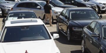 A car dealer walks past cars for sale at a used car dealership in Jersey City, New Jersey, U.S, on Wednesday, May 20, 2020. Governor Phil Murphy has lifted restrictions on in-person auto sales, provided the businesses follow social distancing guidelines, NBC reported.