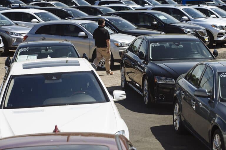 A car dealer walks past cars for sale at a used car dealership in Jersey City, New Jersey, U.S, on Wednesday, May 20, 2020. Governor Phil Murphy has lifted restrictions on in-person auto sales, provided the businesses follow social distancing guidelines, NBC reported.