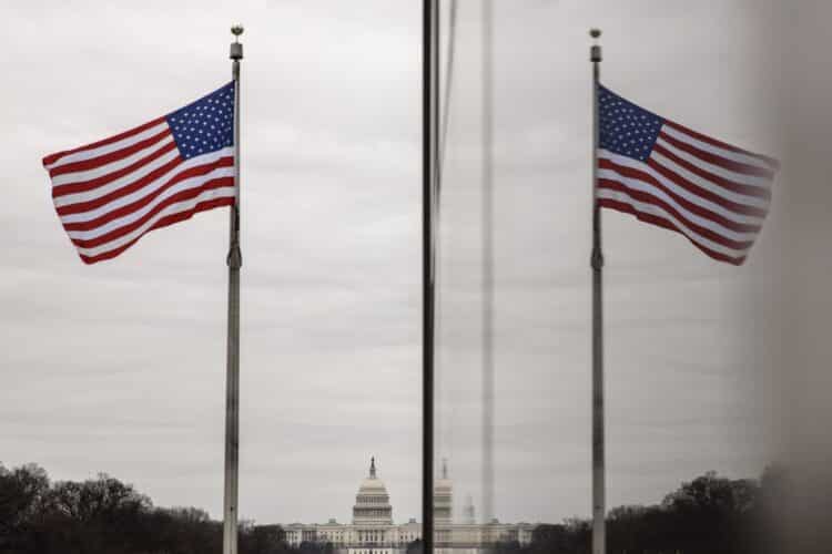 The American flag reflected on building walls in front of the U.S. Capitol building. Photographer: Samuel Corum/Bloomberg