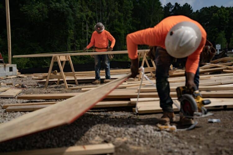 Construction workers wearing orange high-vis gear and hard hats on an active work site