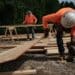 Construction workers wearing orange high-vis gear and hard hats on an active work site