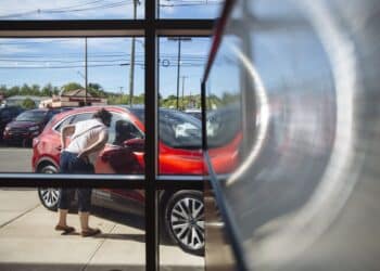 A person looks at a vehicle displayed for sale at a car dealership