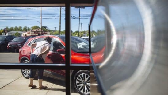 A person looks at a vehicle displayed for sale at a car dealership