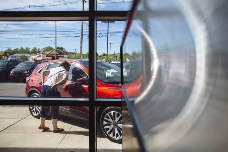 A person looks at a vehicle displayed for sale at a car dealership
