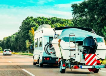 Rv camper car with motor boat on road. caravan and motorhome on trip