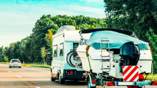 Rv camper car with motor boat on road. caravan and motorhome on trip