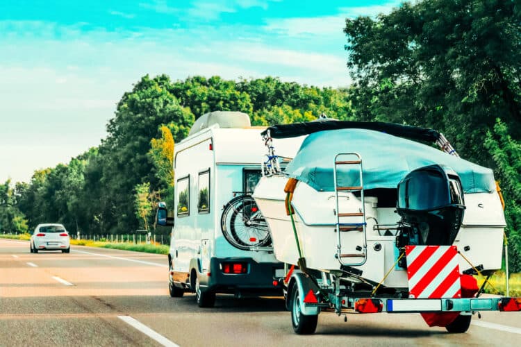 Rv camper car with motor boat on road. caravan and motorhome on trip