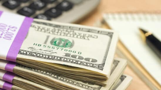 Stack of money by a calculator and paper