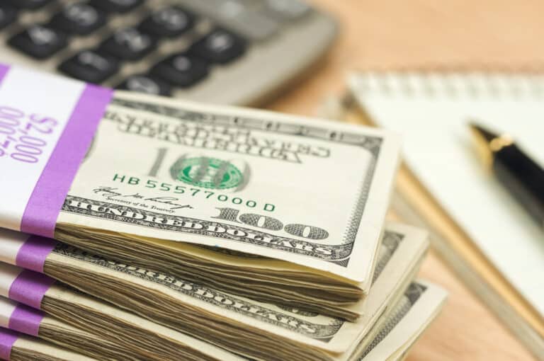 Stack of money by a calculator and paper
