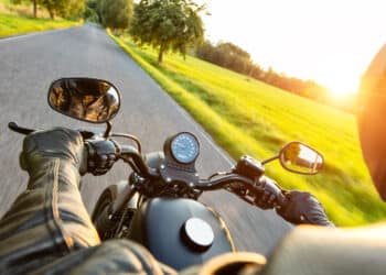 Motorcycle driver riding on motorway in beautiful sunset light. shot from pillion driver view