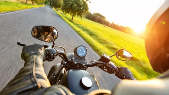 Motorcycle driver riding on motorway in beautiful sunset light. shot from pillion driver view