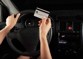 Driver hold credit card infront of car dashboard